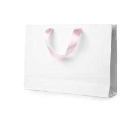 Paper shopping bag with ribbon handles on white background. Mockup for design