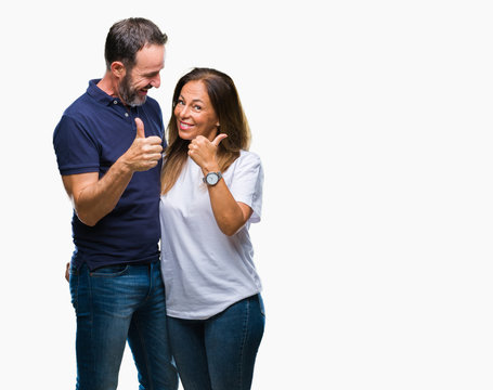 Middle age hispanic casual couple over isolated background doing happy thumbs up gesture with hand. Approving expression looking at the camera with showing success.