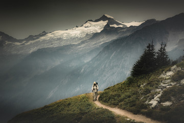 A male hiker is hiking through a valley pass on the back of snowy mountains in North Cascades National Park, Washington, USA