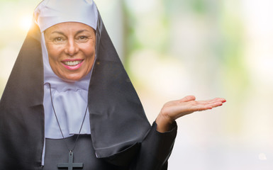 Middle age senior christian catholic nun woman over isolated background smiling cheerful presenting...
