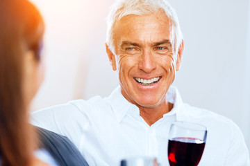 Senior man with holding a glass of wine indoors