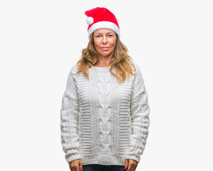 Middle age senior hispanic woman wearing christmas hat over isolated background with serious expression on face. Simple and natural looking at the camera.