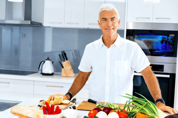 Portrait of a smart senior man standing in kitchen