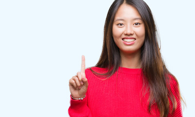 Young asian woman wearing winter sweater over isolated background showing and pointing up with finger number one while smiling confident and happy.