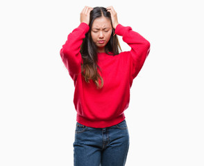 Obraz na płótnie Canvas Young asian woman wearing winter sweater over isolated background suffering from headache desperate and stressed because pain and migraine. Hands on head.