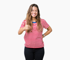 Obraz na płótnie Canvas Young beautiful brunette woman wearing stripes t-shirt over isolated background doing happy thumbs up gesture with hand. Approving expression looking at the camera showing success.