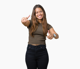 Obraz premium Young beautiful brunette woman over isolated background approving doing positive gesture with hand, thumbs up smiling and happy for success. Looking at the camera, winner gesture.