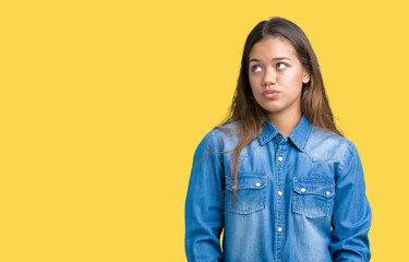 Young beautiful brunette woman wearing blue denim shirt over isolated background making fish face with lips, crazy and comical gesture. Funny expression.