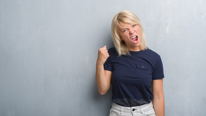 Adult caucasian woman over grunge grey wall annoyed and frustrated shouting with anger, crazy and yelling with raised hand, anger concept