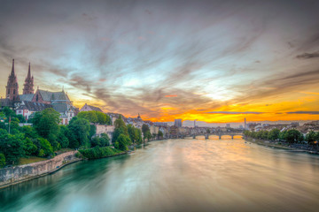 Sunset view of riverside of Rhine in Basel dominated by majestic building of Munster church,...