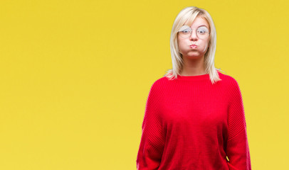 Young beautiful blonde woman wearing sweater and glasses over isolated background puffing cheeks...