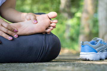 oman suffering from pain in foot while running in a park 