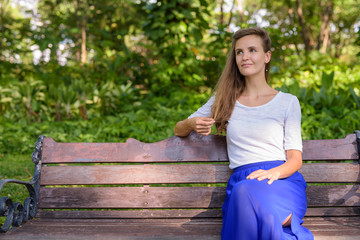 Beautiful woman thinking while touching her hair and sitting on 