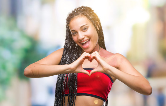 Young braided hair african american with pigmentation blemish birth mark over isolated background smiling in love showing heart symbol and shape with hands. Romantic concept.