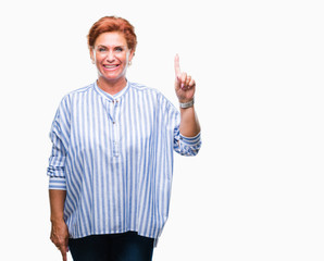 Naklejka premium Atrractive senior caucasian redhead woman over isolated background showing and pointing up with finger number one while smiling confident and happy.