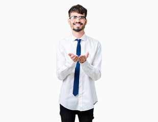 Young handsome business man wearing glasses over isolated background Smiling with hands palms together receiving or giving gesture. Hold and protection