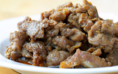 Stir fry pork slice with coconut sugar sprinkle with fried shallot slice (Sweet pork) in white dish on wooden table, delicious Thai food