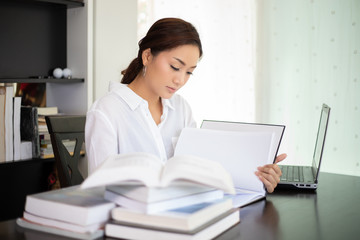 Asian women student smiling and reading a book for relaxation and final exam