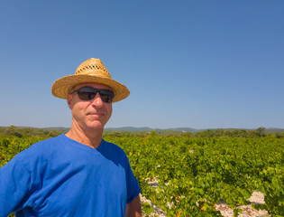 A winegrower stands in a field among vineyards