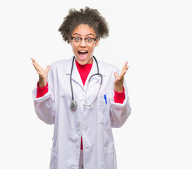 Young afro american doctor woman over isolated background celebrating crazy and amazed for success with arms raised and open eyes screaming excited. Winner concept