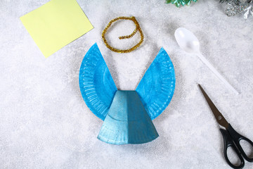 The process of creating your own Christmas angel from a disposable cardboard plate, a plastic spoon and paper. Christmas decor. Handmade, hobby, DIY.