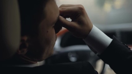 Tired businessman taking off glasses, sitting in car, suffering migraine, health