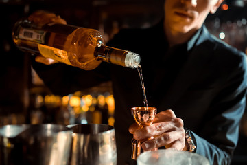 The bartender strains a cocktail in a glass at a nightclub, beach, pub, restaurant