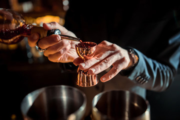 The bartender strains a cocktail in a glass at a nightclub, beach, pub, restaurant