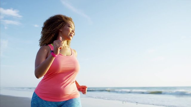 Active afro hair Ethnic African American female speed walking by the ocean for fitness activity and wellbeing health 