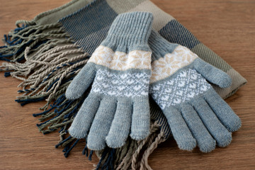 Gray gloves on a gray scarf. Warm gloves for cold autumn and winter seasons. Gloves and a scarf are accessories for clothing. Fashion and style in clothes.