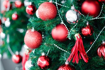 Closeup of red bauble hanging from a decorated Christmas tree. Happy new year concept.