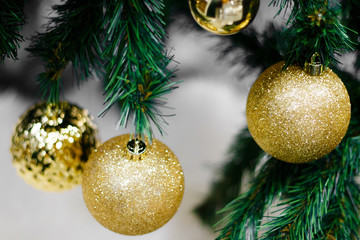 Closeup of gold bauble hanging from a decorated Christmas tree. Shiny happy new year concept.