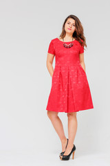 Young charming brunette woman with curly hair in elegant red dre