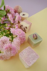 Bath bombs set with rose extract. round and square bath truffle, pink rose flower on yellow lilac  background.Organic cosmetics for body