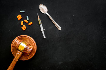 Drugs addiction, arrest for drugs. Pills, spoon with powder, syringe on black background top view copy space