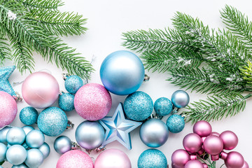 New Year and Christmas atmosphere. Decorate festive christmas tree. Christmas tree decoration.   Blue and pink balls and stars near spruce branch, pine fir on white background top view