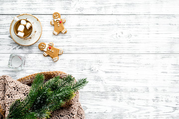 Relaxing, cozy winter evening concept. Hot mug of cocoa near christmas gingerbread man, fir branches, wool blanket on white wooden background top view space for text