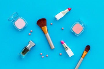 Set of pink cosmetics. Lipstick, bulk, eyeshadow, perfume near brushes on blue background top view