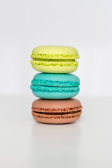 Turquoise, brown and green macarons on the white table. Close-up, front view, copy space