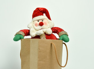 Santa Claus in a paper shopping bag ready for the holiday to come. Santa Claus is coming to town.