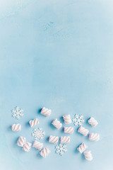 Christmas marshmallows and snowflakes on a blue concrete background.Top view.