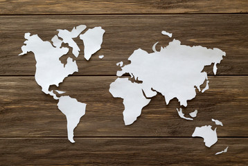 World map cutted from white paper on the wooden background. Flat lay, top view, copy space, mock up