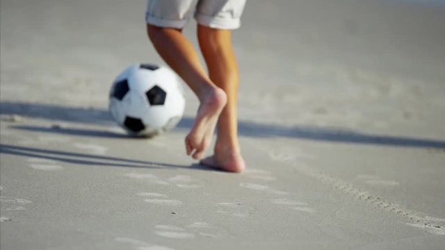 Latin American dad and son playing together on beach holiday with soccer ball