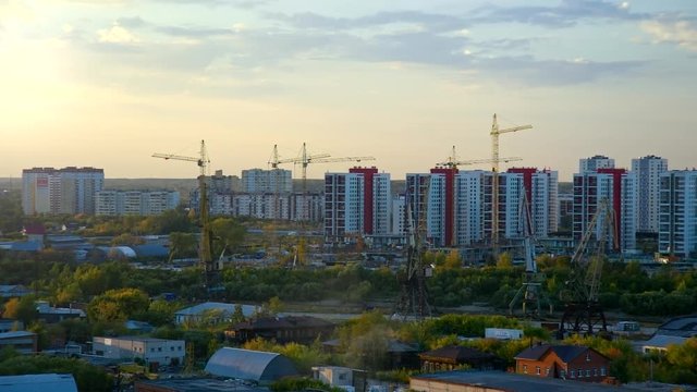tower cranes on buliding site in modern city against sunset 