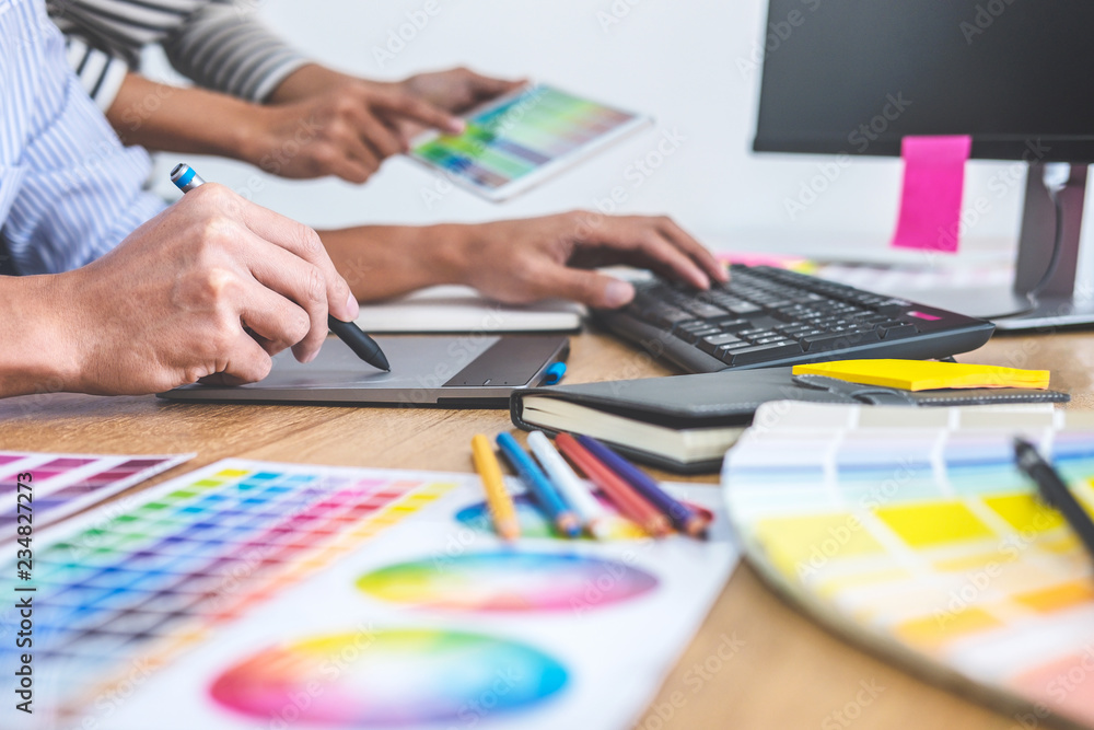 Poster Two colleagues creative graphic designer working on color selection and drawing on graphics tablet at workplace, Color swatch samples chart for selection coloring