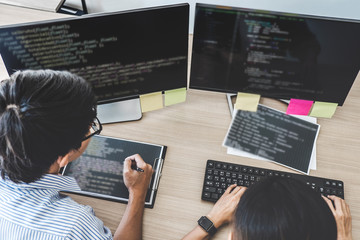 Two professional programmers cooperating at Developing programming and website working in a software develop company office, writing codes and typing data code