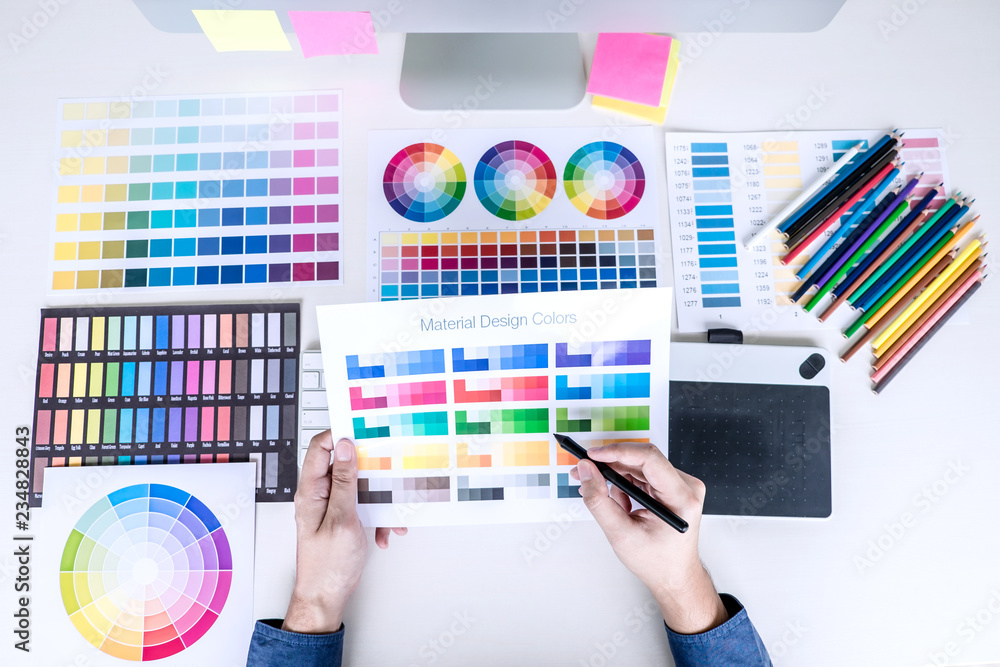 Poster male creative graphic designer working on color selection and color swatches, drawing on graphics ta