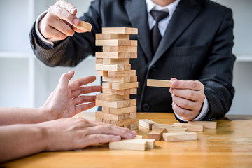 Images of hand of businesspeople placing and pulling wood block on the tower, Alternative risk...