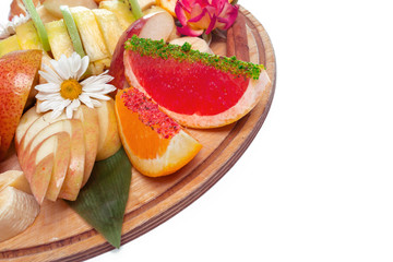 Tropical fruits assortment on a wooden plate isolated on white background