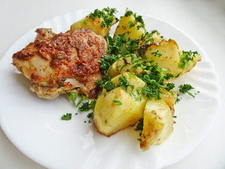 Appetizing dish - baked chicken and potatoes on a platter. Delicious and nutritious dinner